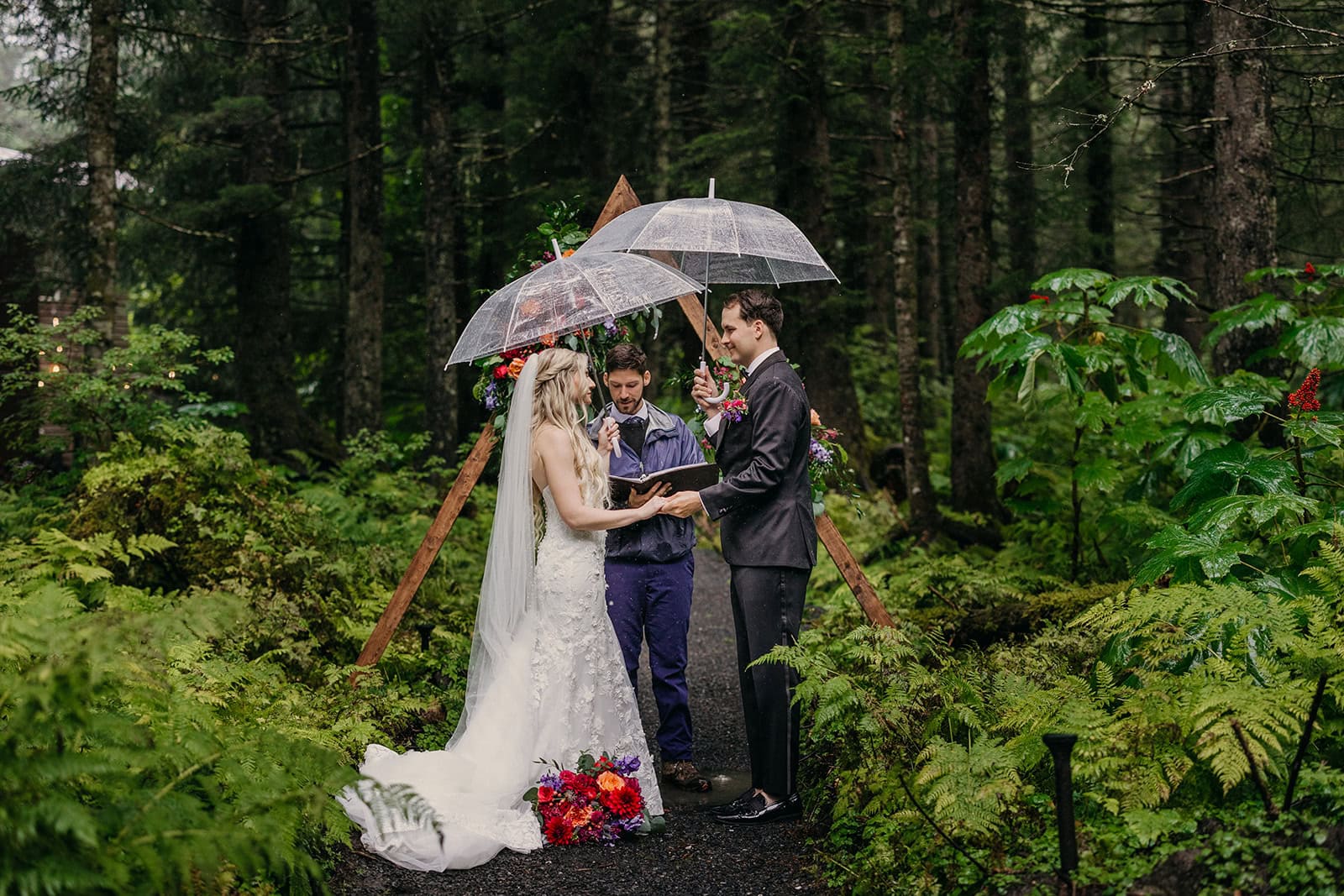 An elopement ceremony held during the rain in a lush forest.