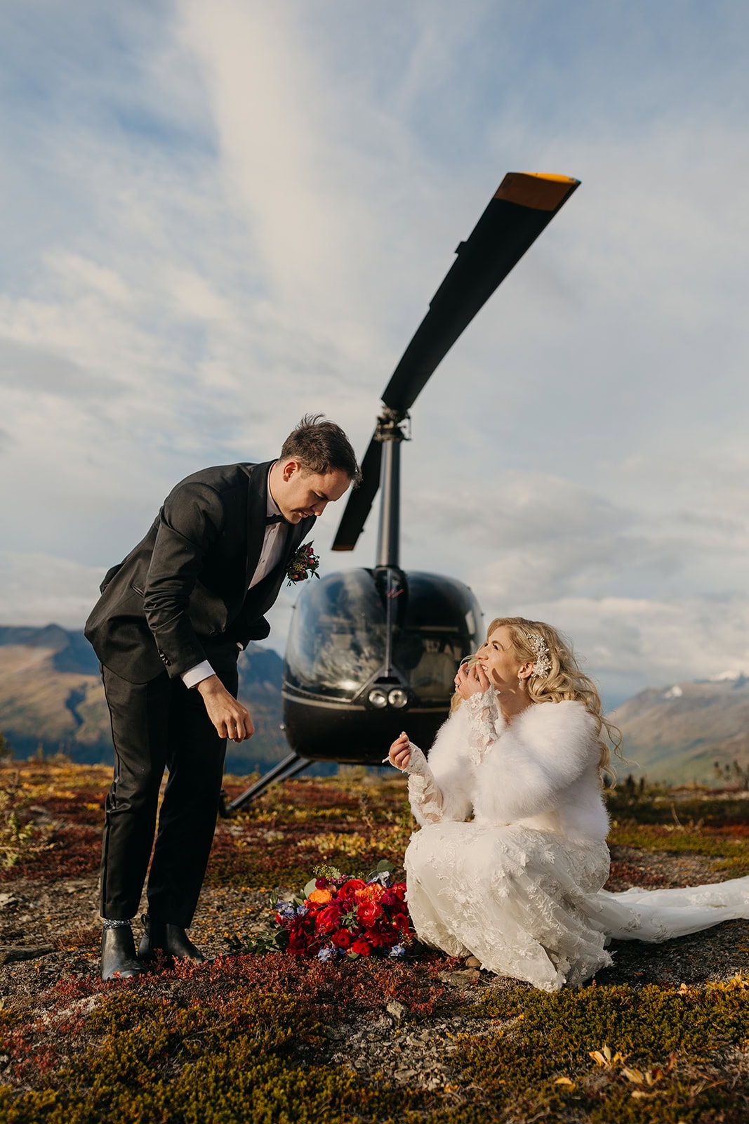 A couple eats fresh berries in Alaska by a helicopter.
