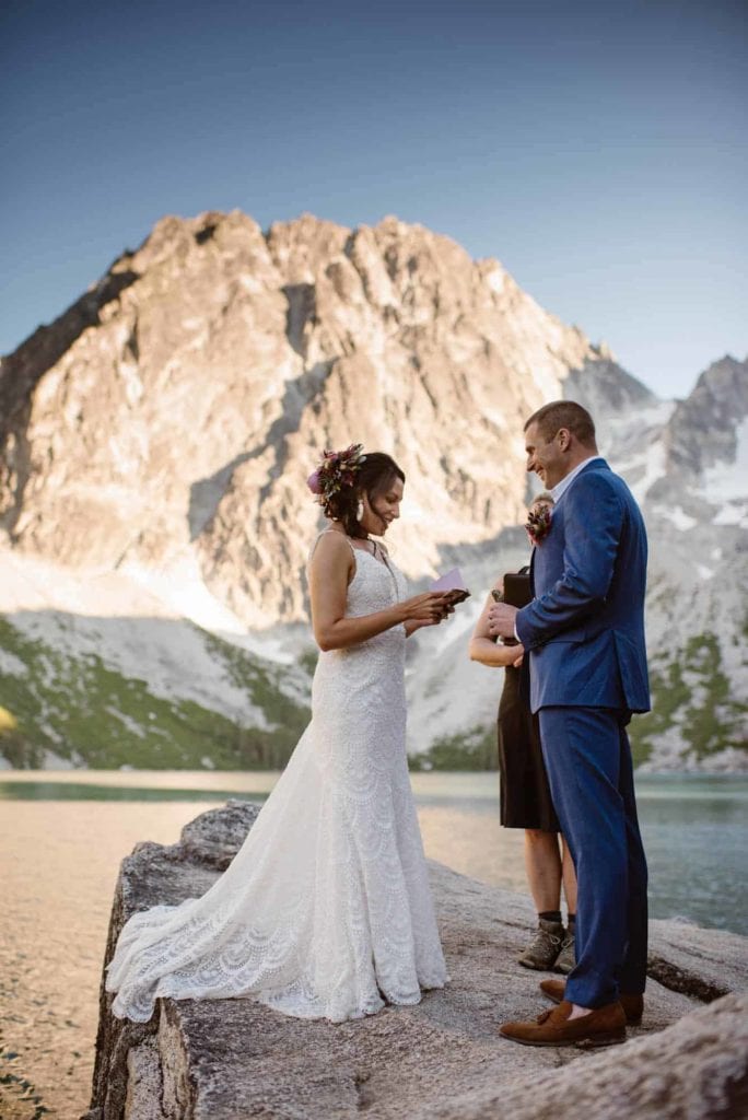 A couple reads their vows to each other by Lake Colchuck.