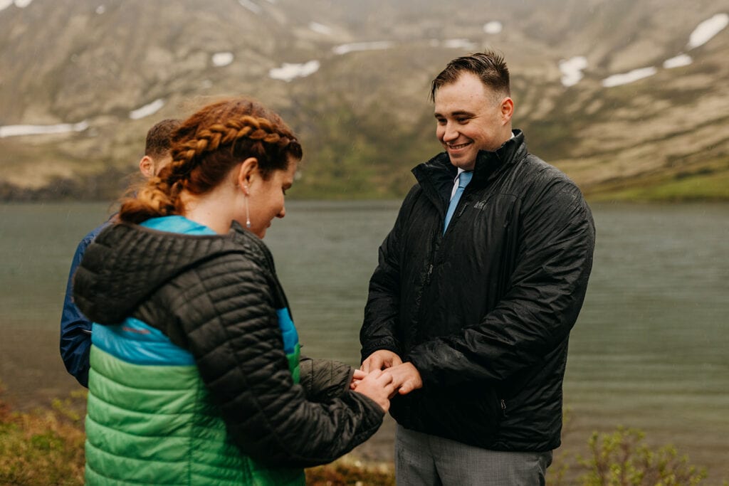 The bride places the ring on the grooms finger.