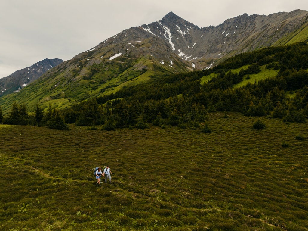 A couple hikes through the chugach mountains on their way to their backpacking eloping ceremony location.