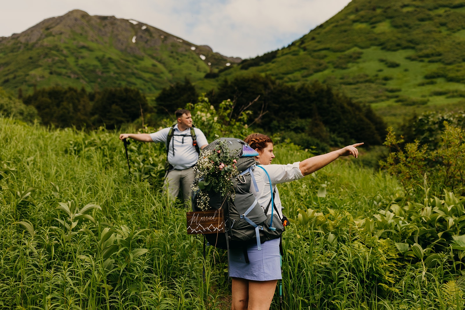 A bride points out something on the trail while backpacking in Alaska for their elopement.