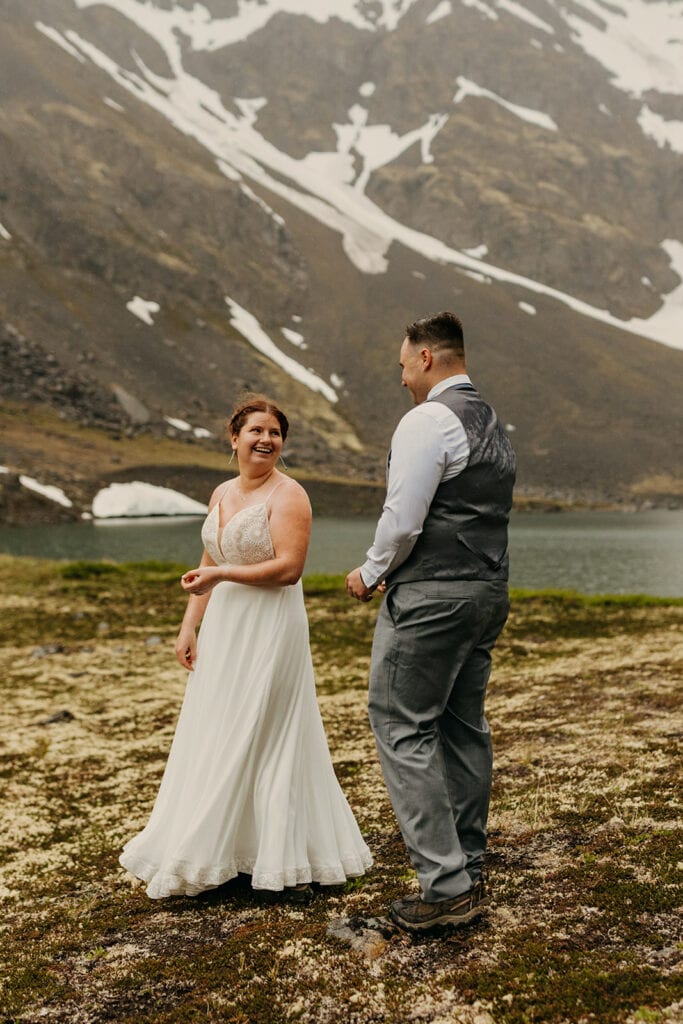 The bride smiles as she shows off her dress to the groom.