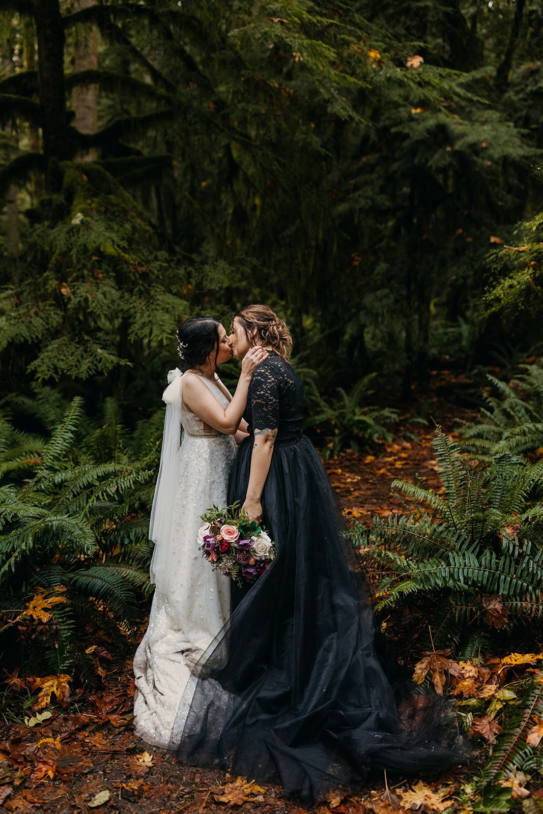 Two brides share a kiss in the forest on their elopement day.