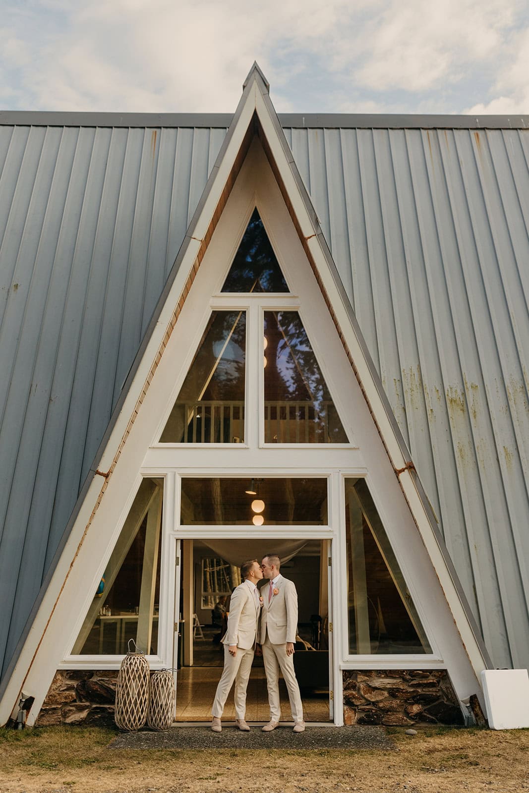 A couple walks out of a venue sharing a kiss on their wedding day.