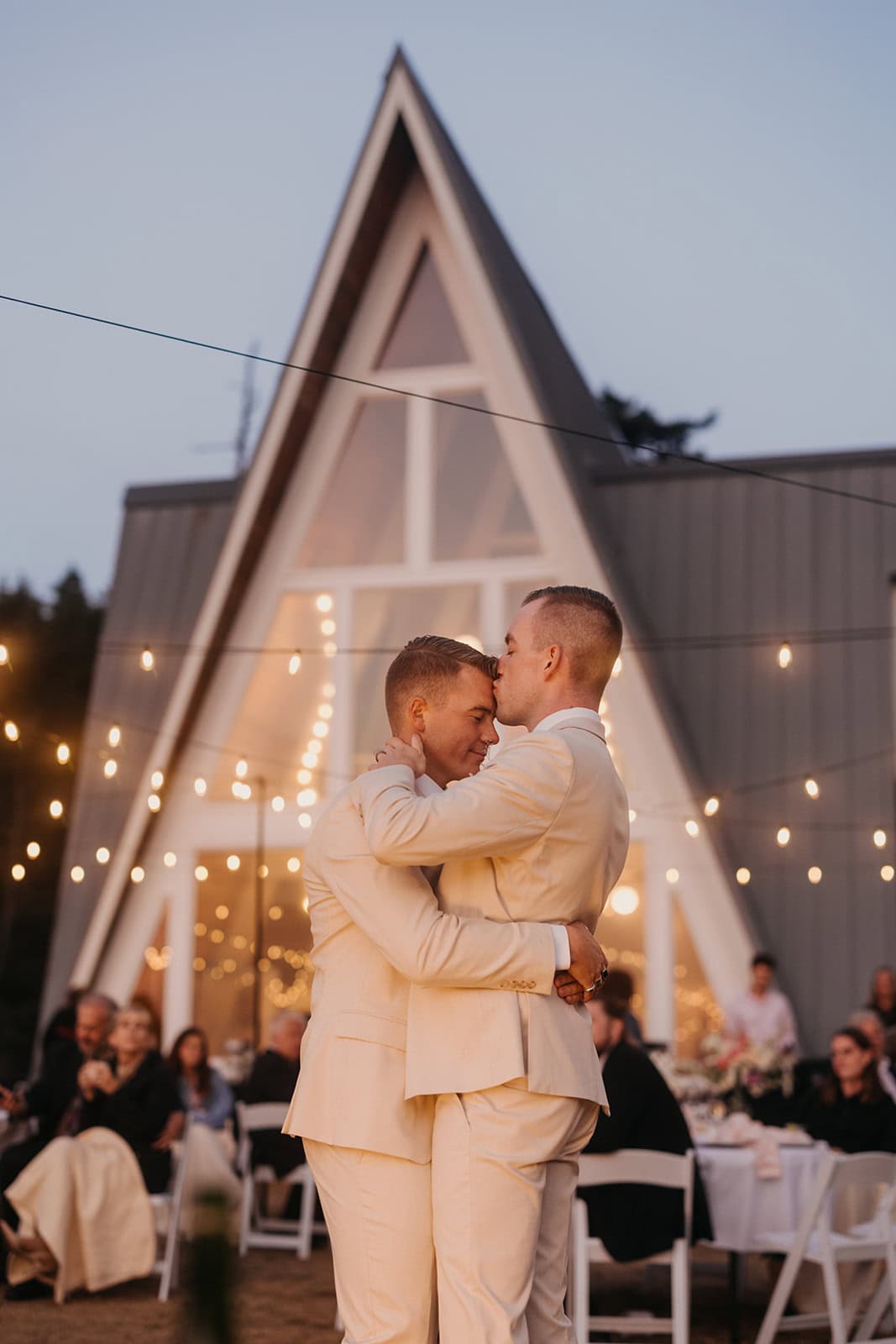 A couple shares their first dance under twinkle lights at their venue.
