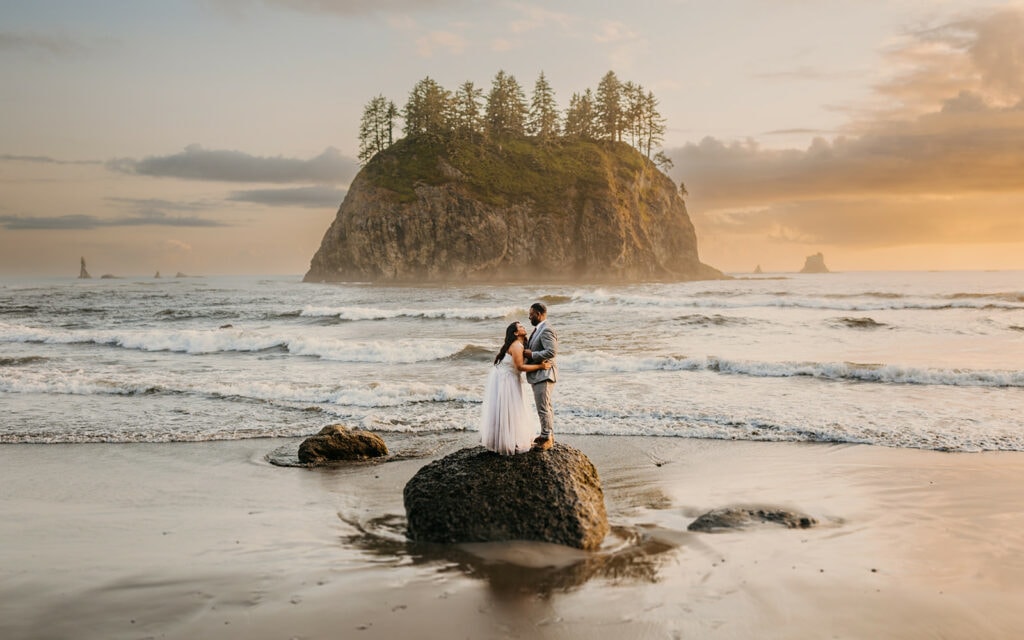 A couple celebrates together getting married as the sun starts to set on the coast.