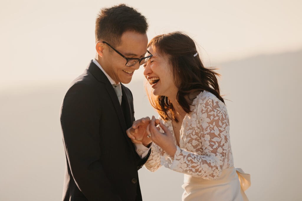 A bride laughs as she places the ring on her grooms finger. 