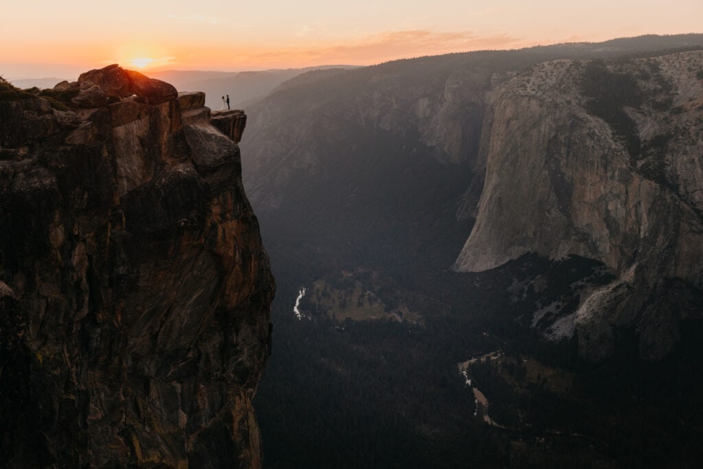 A couple stands on a vista overlook in Yosemite National Park at sunset. 