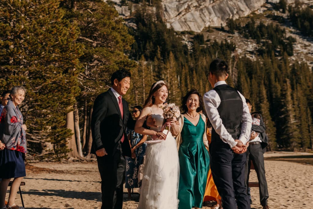 A bride is walked down the isle by her mother and father. 