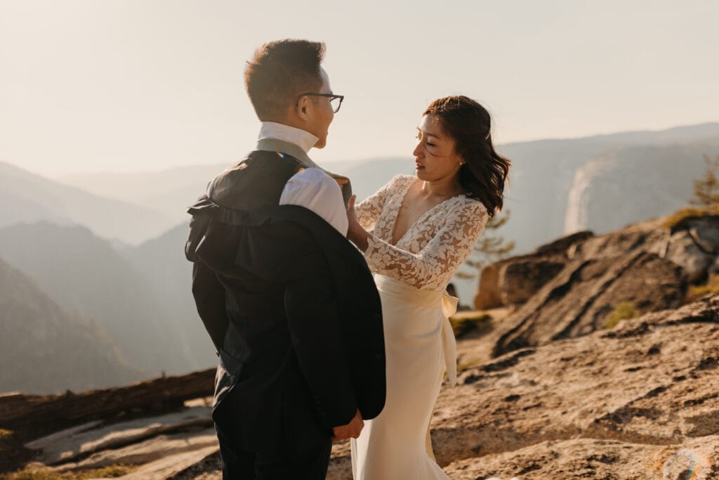 A bride helps her groom with his tie after their first look. 