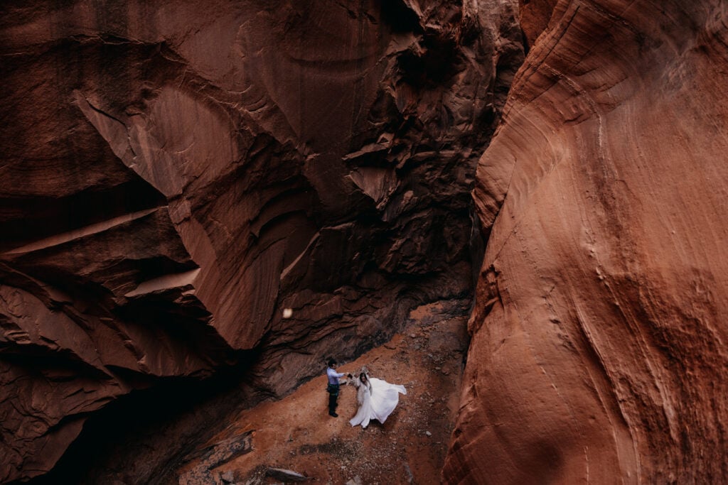 A bride spins in a slot canyon in moab as a leaf falls.