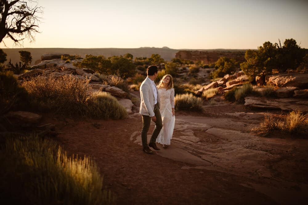 A bride smiles at her groom as they walk together through the desert.