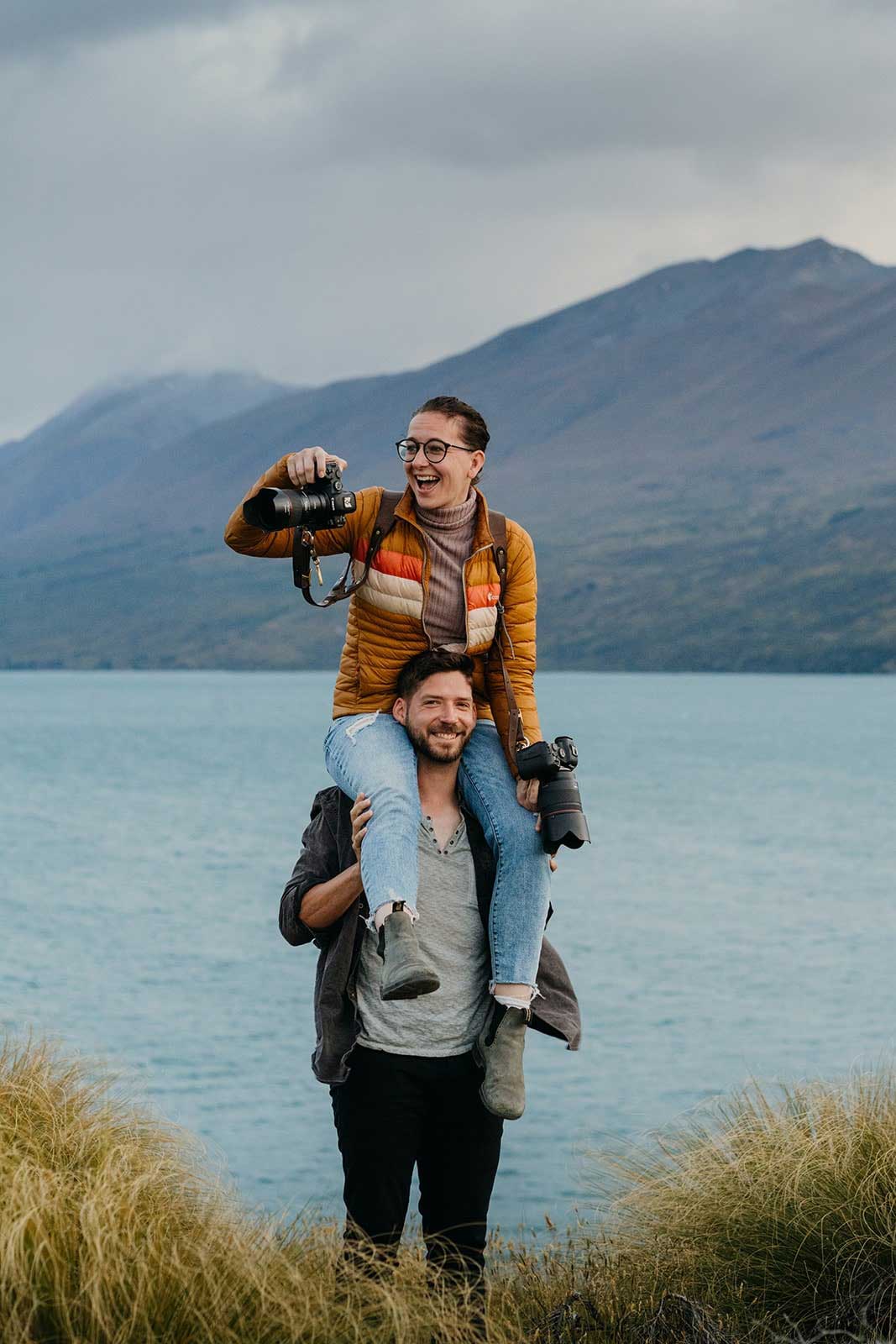 A photographer takes a photo while on the shoulders of her assistant.