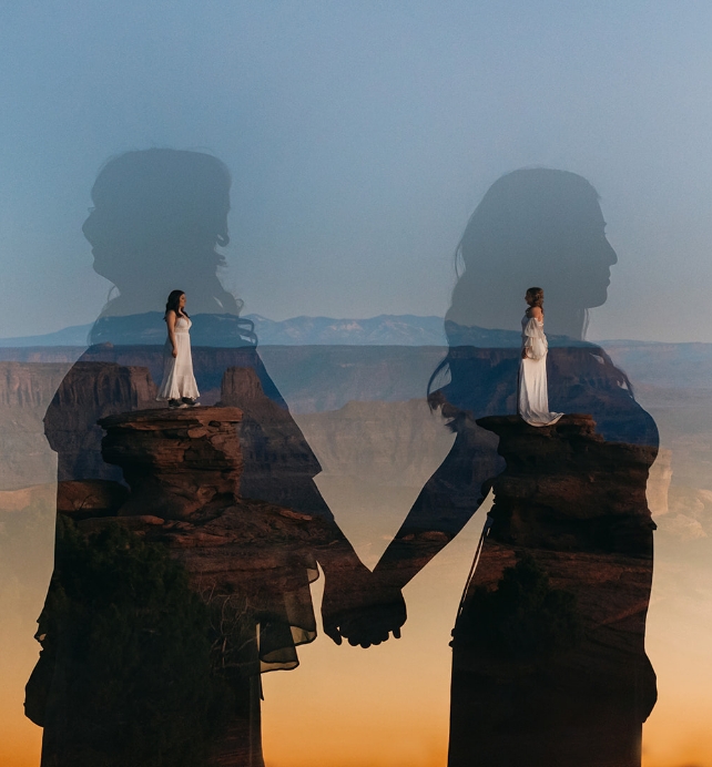 A couple stands in the desert in their wedding outfits.