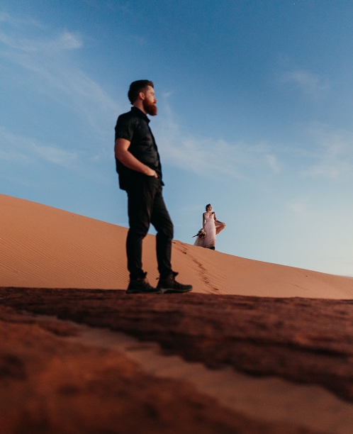 Two people stand on dunes in Moab on their elopement day.