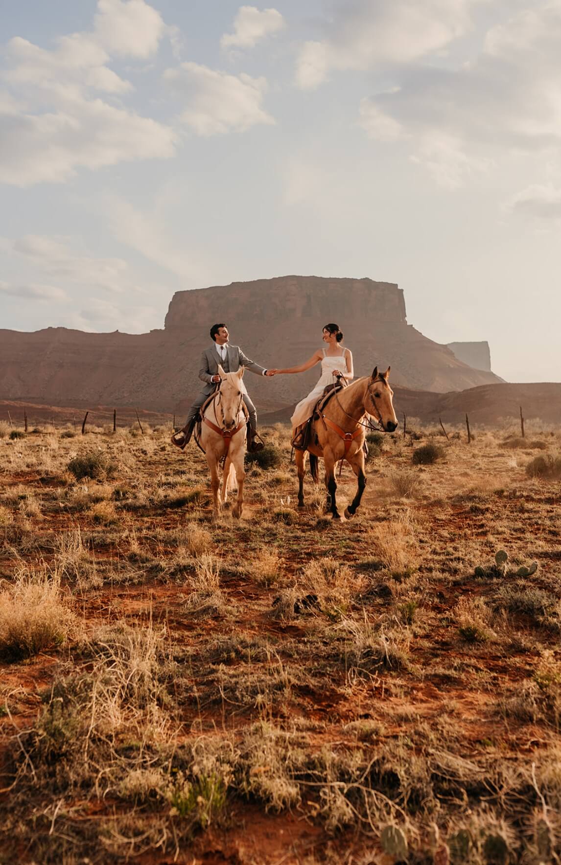 A couple rides horses during a Moab elopement in the desert.