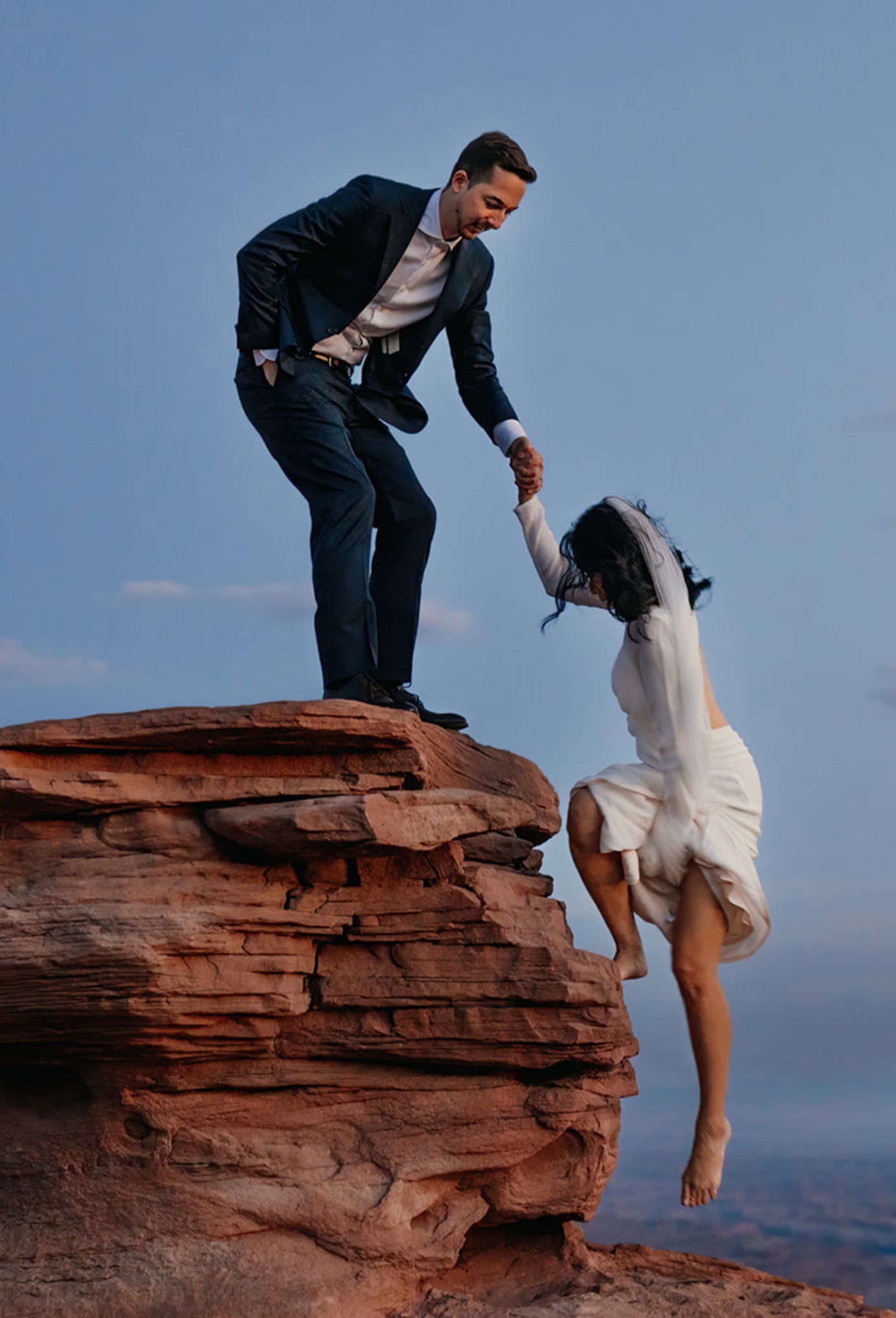 One partner pulls the other up onto a rock.