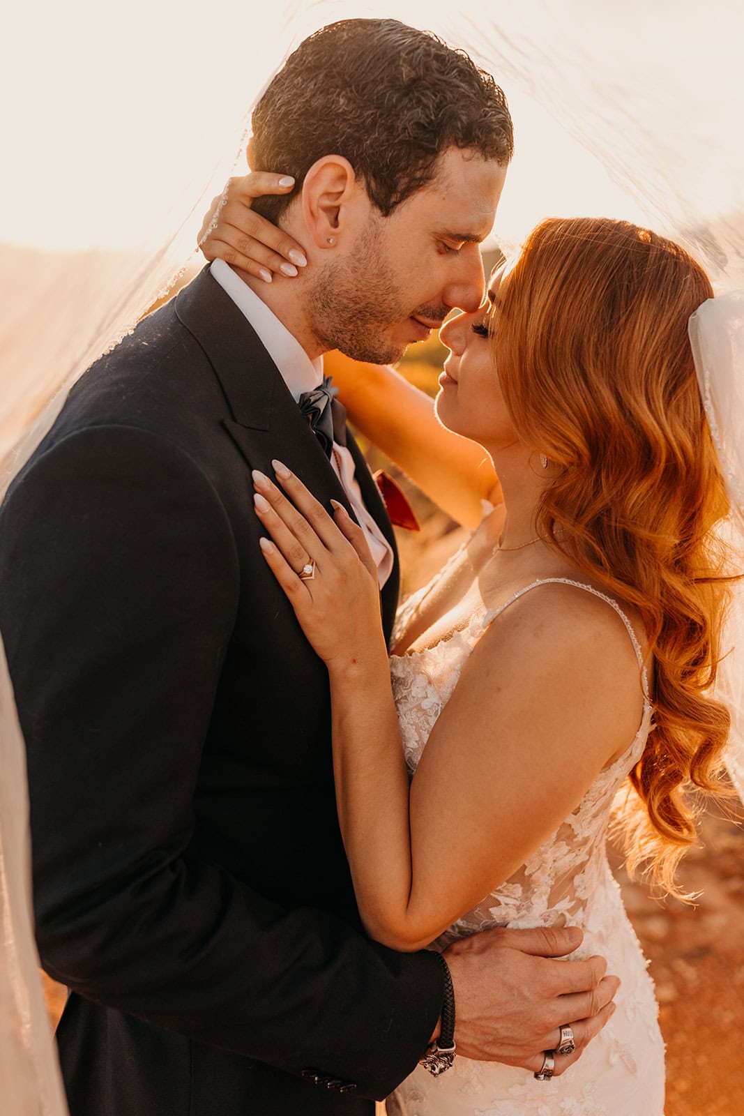 A bride and groom share an intimate moment under the bride's veil. 