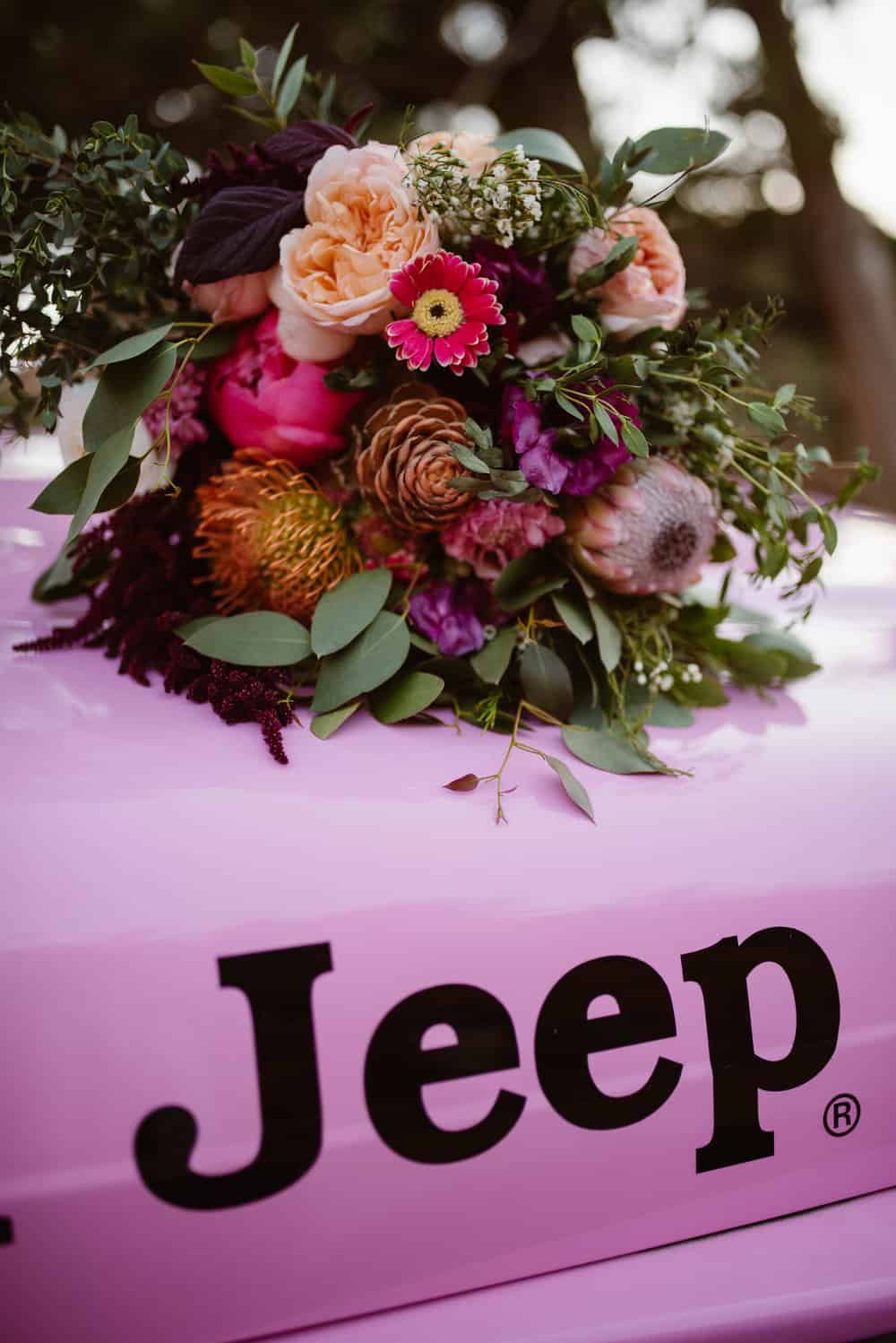 Flowers lay on top of the hood of the jeep.