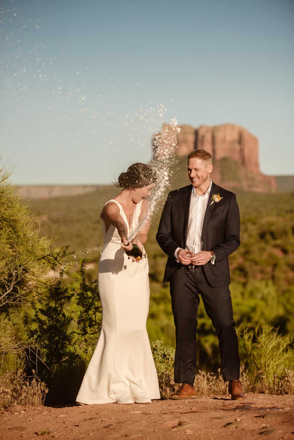 The bride and groom spray a bottle of champagne. 