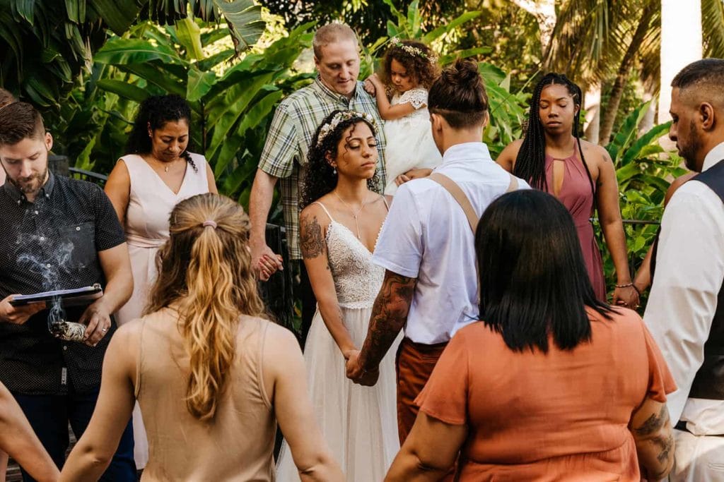 A bride and groom circled by their wedding guests during a saging ceremony.