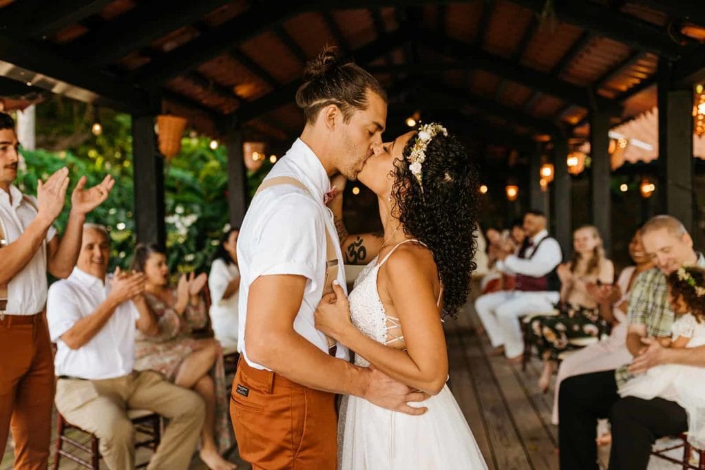 The bride and groom share a first kiss as their guest cheer them on.
