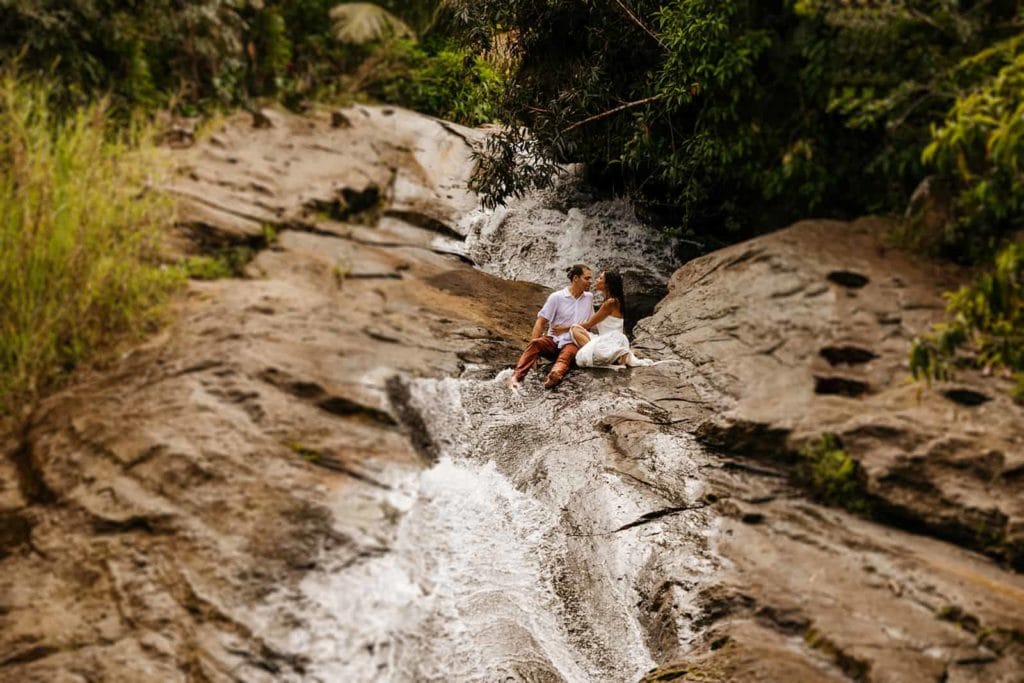 A bride and groom kiss at the top of a natural water slide in Puerto Rico deep in the rainforest.