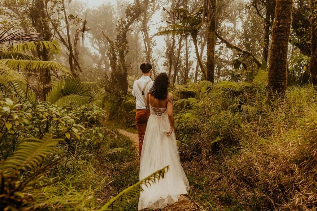 a groom guides his bride through the woods of Puerto Rico.