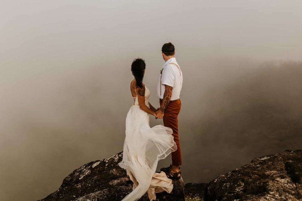 A couple takes in the view as the wind and fog surrounds them.