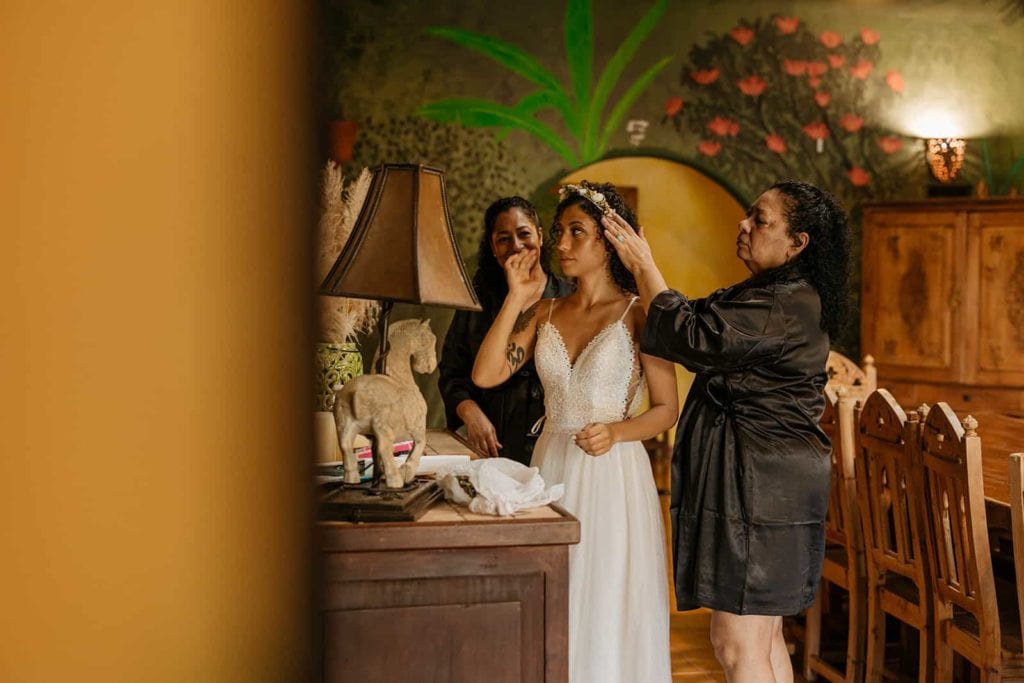 The brides mom and grandmom help her get ready for her wedding day.