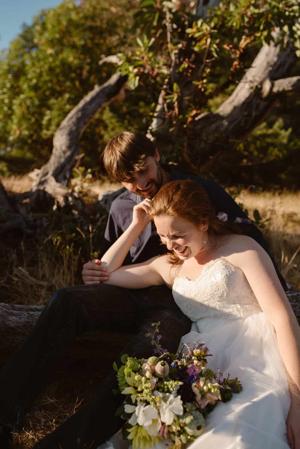 A man and woman laugh together as they sit and enjoy the sun.