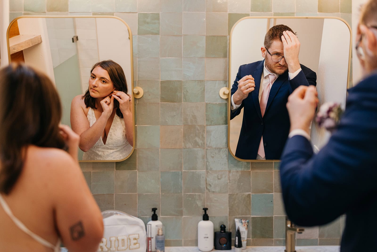 A bride and groom get ready in the bathroom together for their wedding day. 