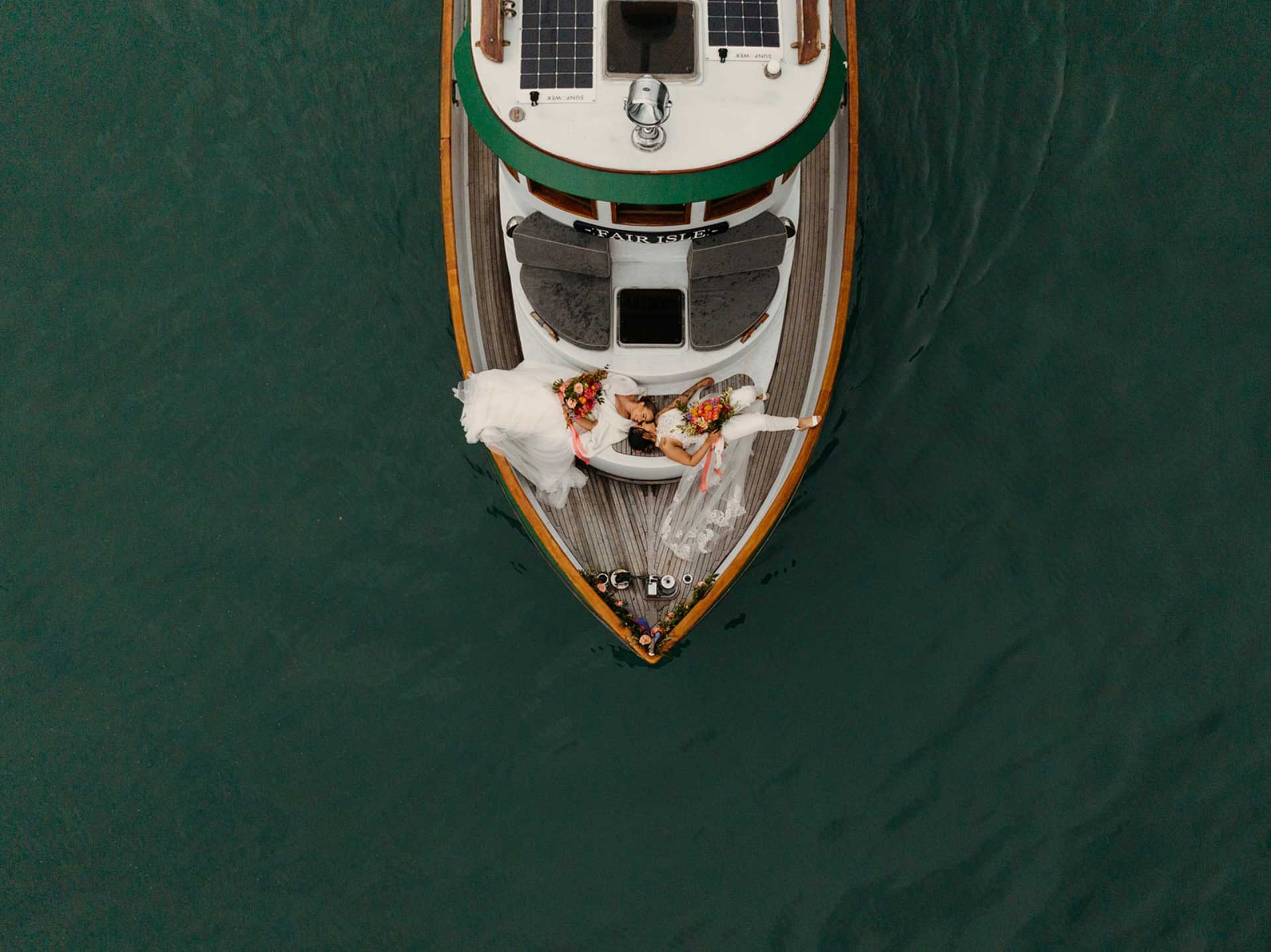 Two brides on lay on a boat together during their private elopement.