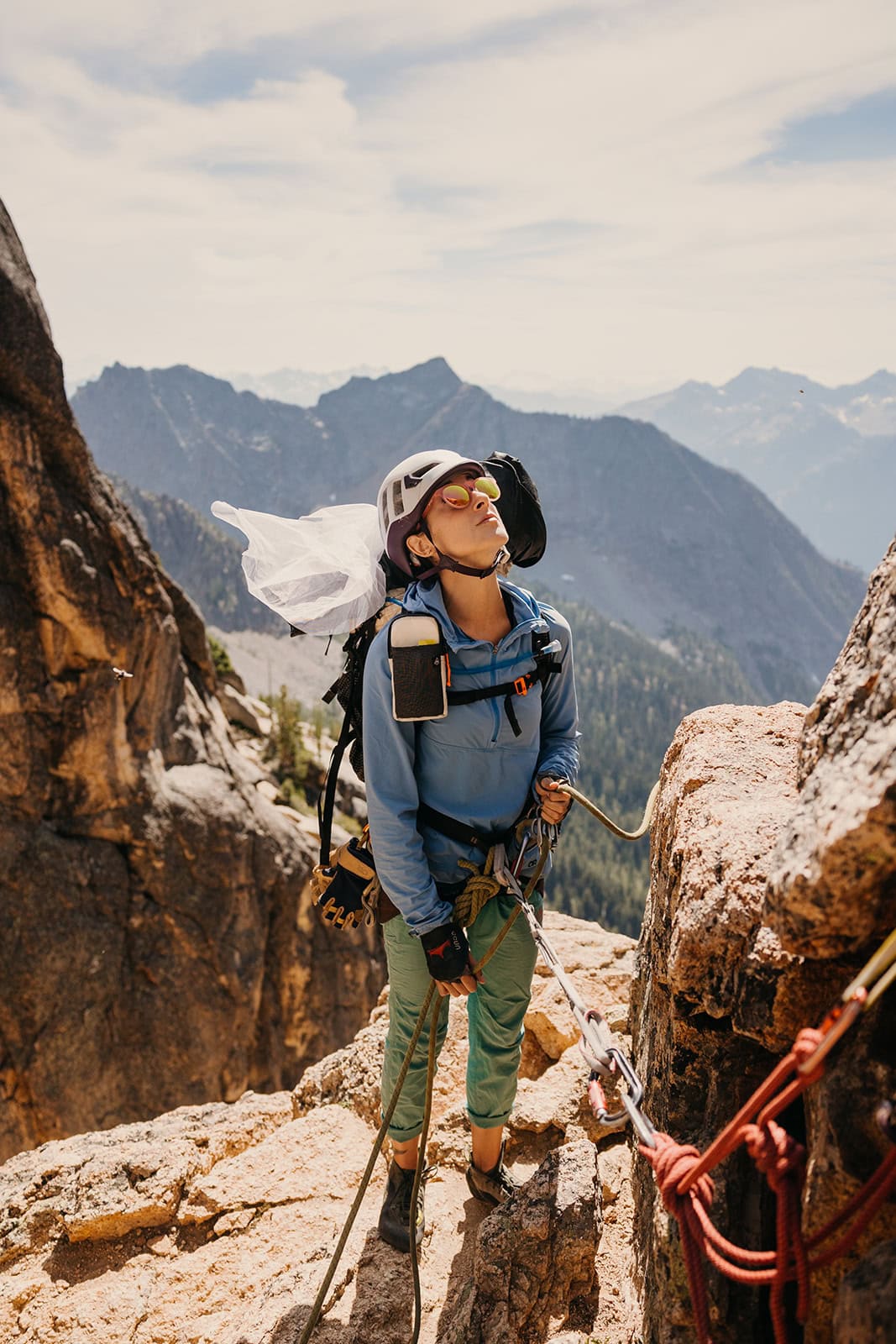 Someone in the mountains looking up at their partner as they belay from below