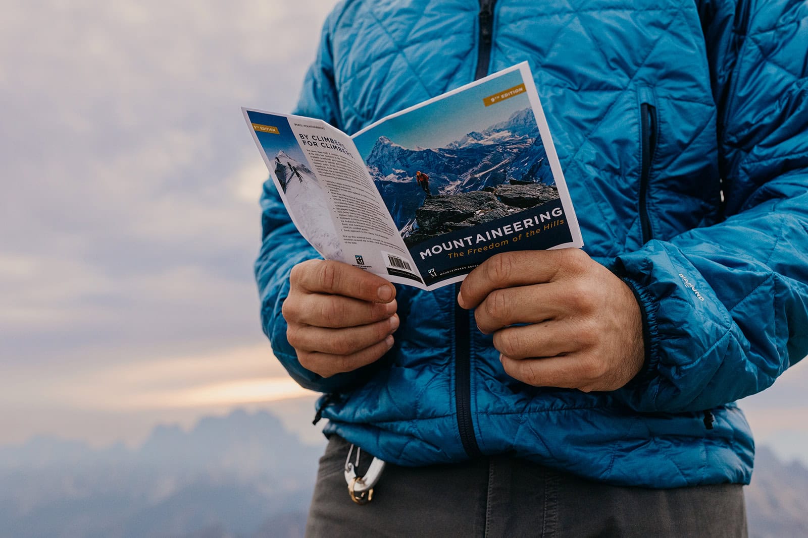 A detail shot of a man holding a book that reads mountaineers.