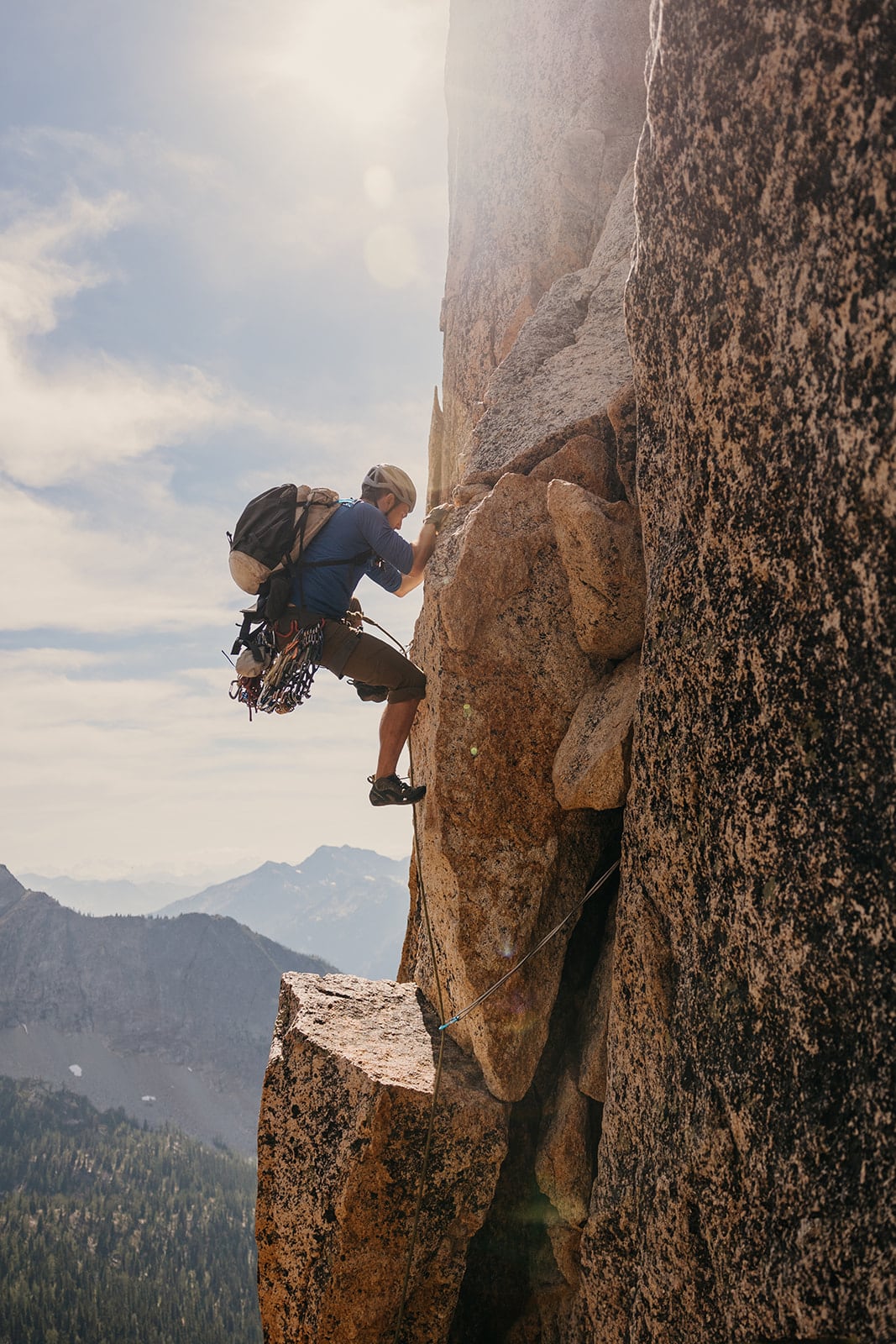 Someone climbing up a mountain while wearing a backpack