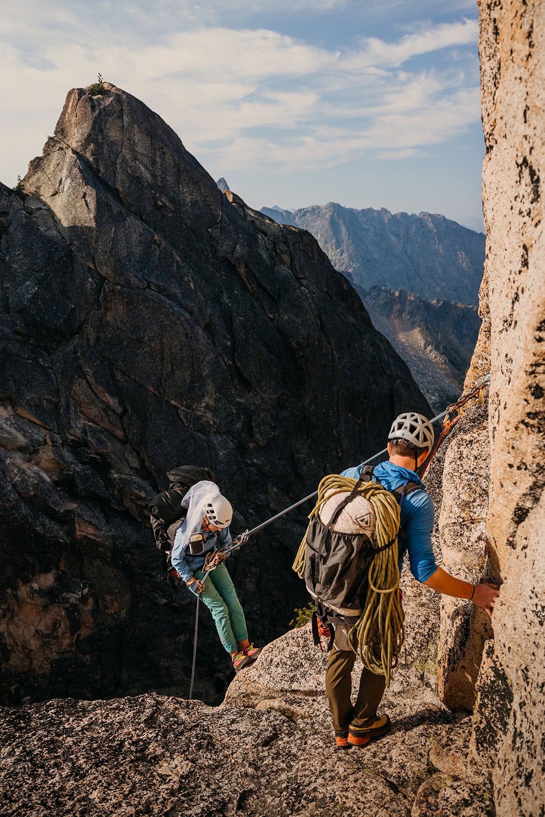 Two people setting up to rappel down a mountain.