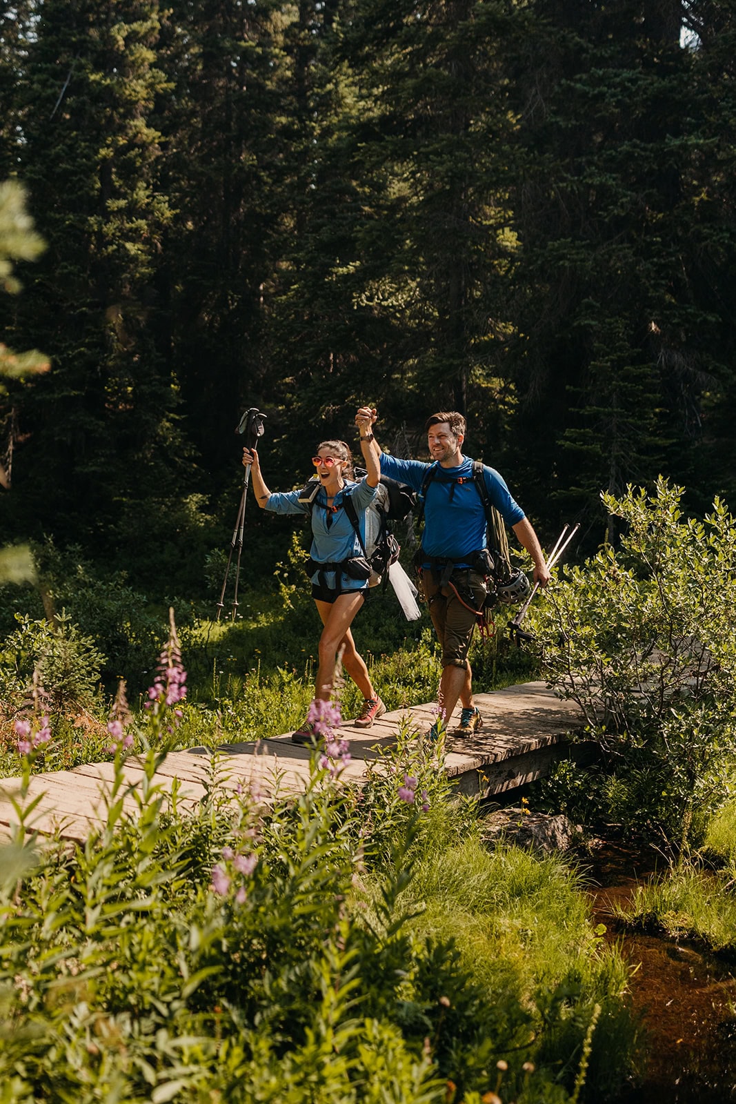 A couple hold hands and celebrate walking together on a trail.