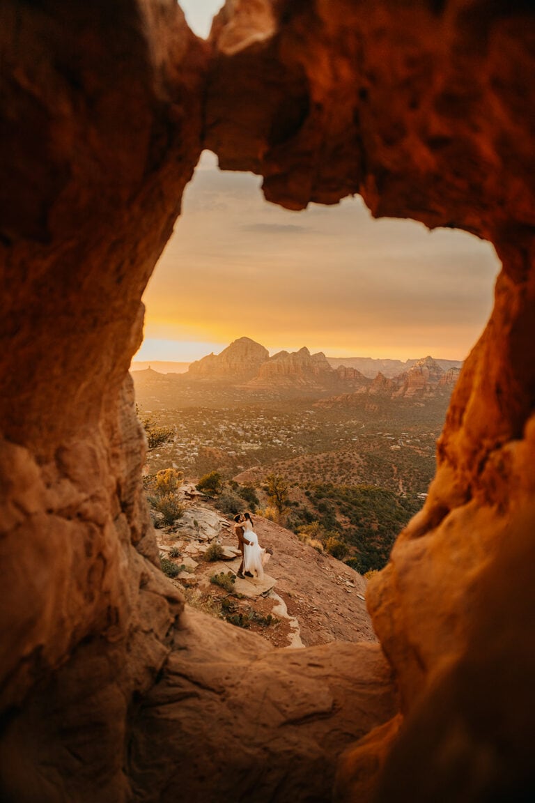 A sunset view through an arch way of a couple dancing.
