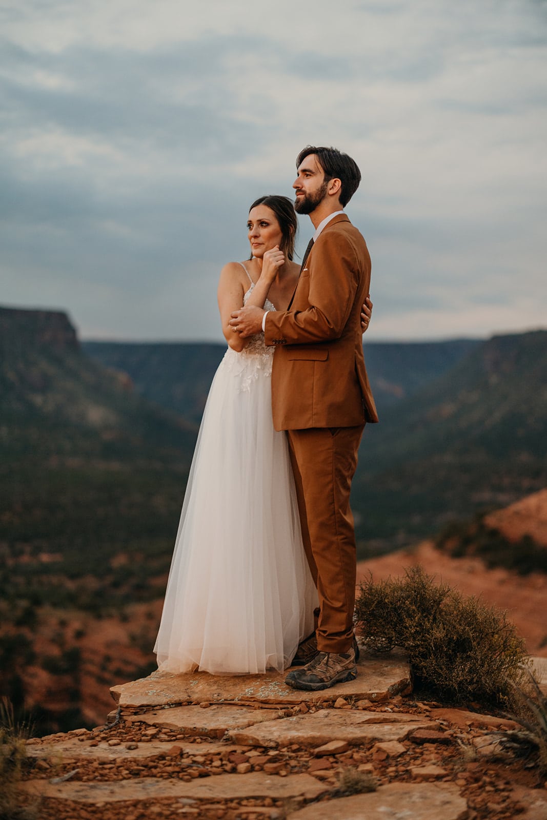 A bride wipes her tears as she watches sunset on her elopement day.