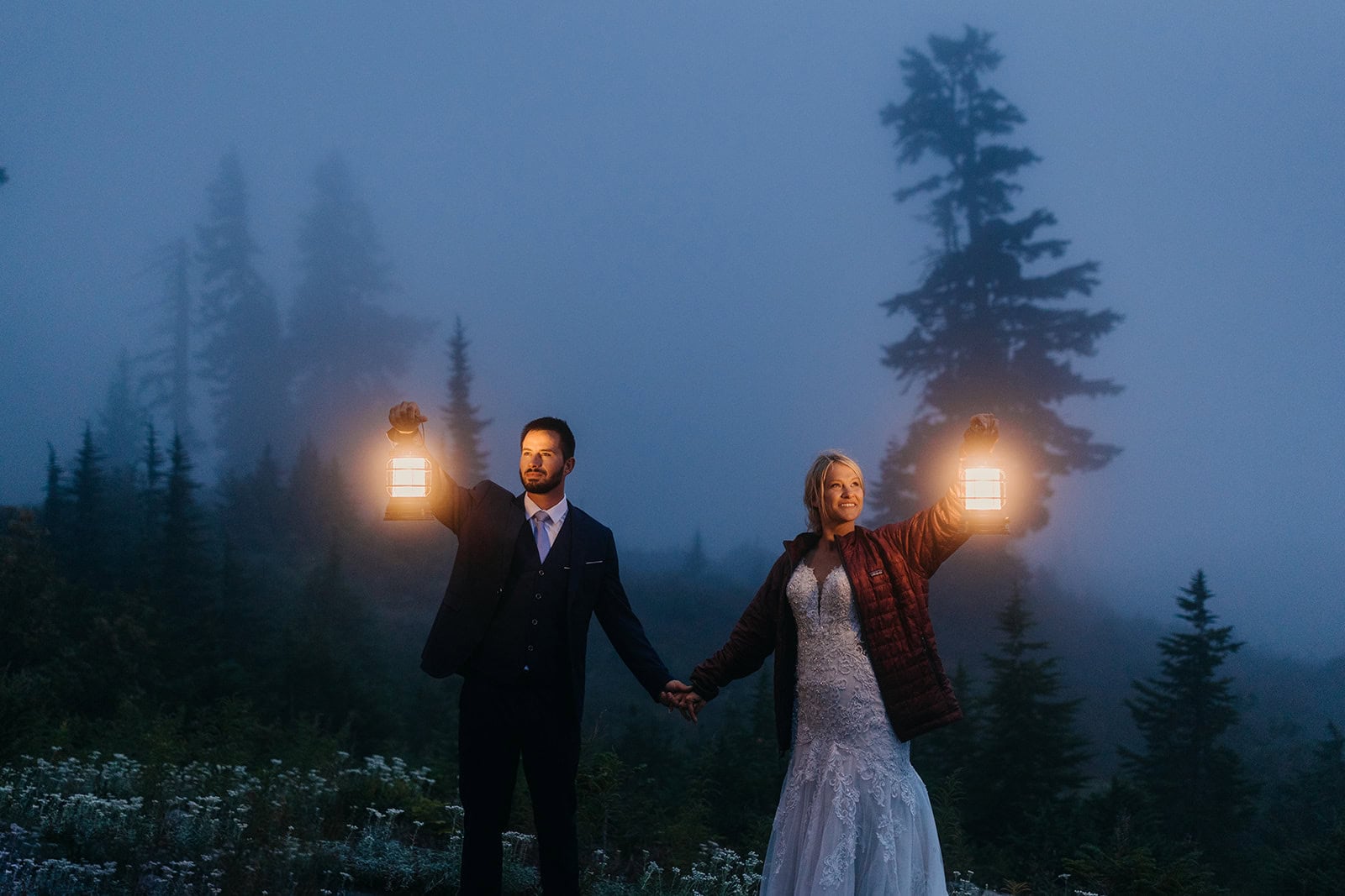 A couple holds lanterns in the foggy on their wedding night.