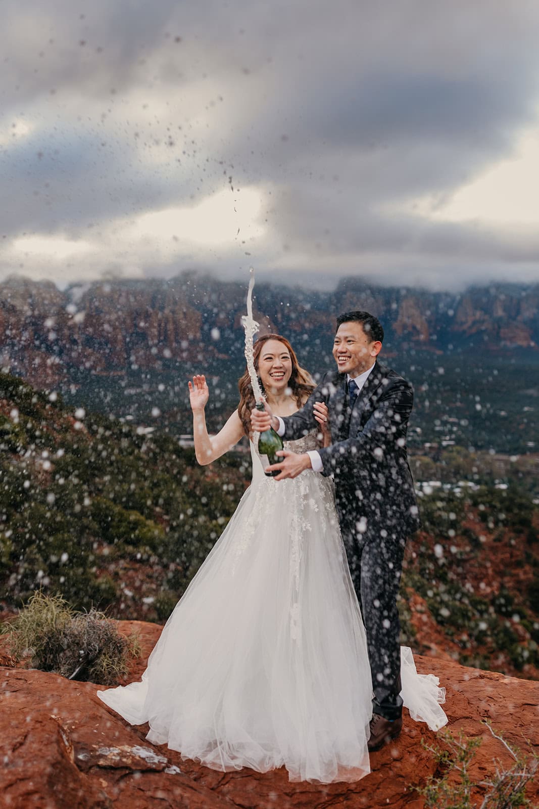 A couple pops champagne at their elopement on a winter morning in Sedona. 