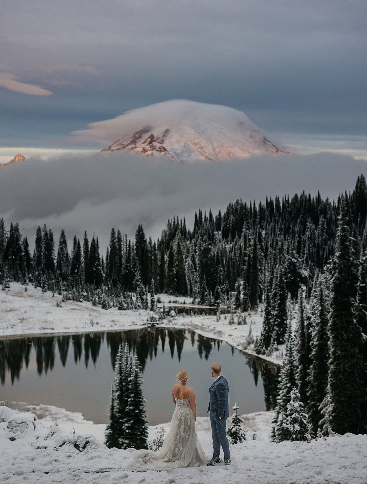 A couple watches the alpine glow on a snowy mount rainier.