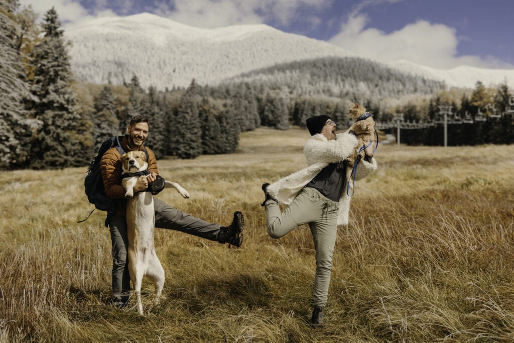 A couple poses for a photo with their dog and cat. 
