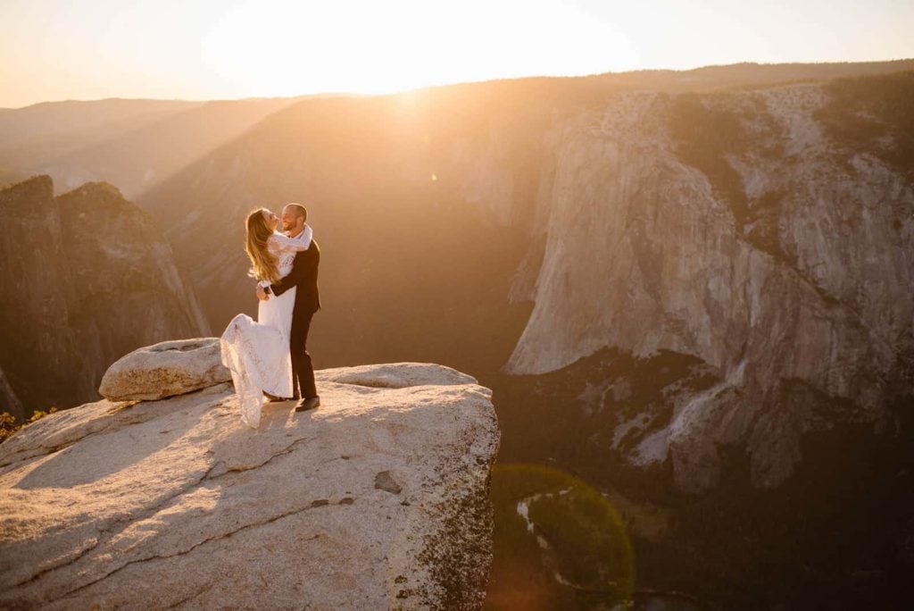 A groom picks up his bride in the sunset light at Taft Point.